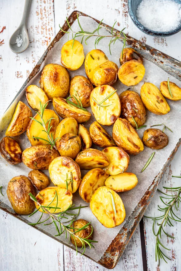 Rosmarinkartoffeln Ofen auf einem Backblech verteilt, frisch gebacken mit Rosmarin und grobem Meersalz