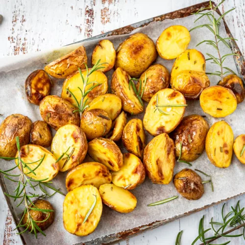 Goldbraune Kartoffelhälften mit Rosmarin direkt vom Blech serviert, einfache und aromatische Beilage aus dem Ofen