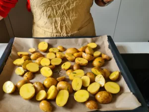 Marinierte Kartoffeln werden auf Backblech verteilt