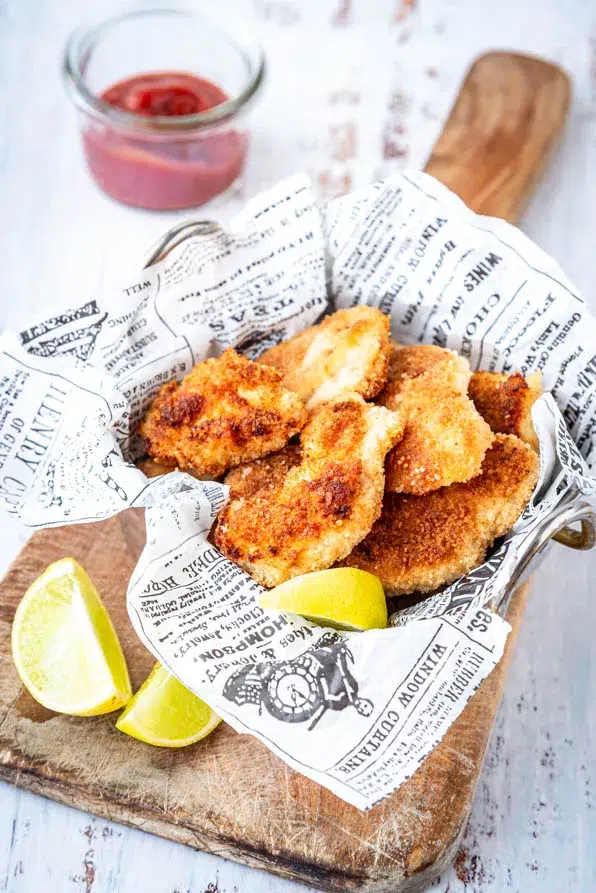 Selbstgemachte Chicken Nuggets knusprig gebraten und serviert mit Dip und Zitrone