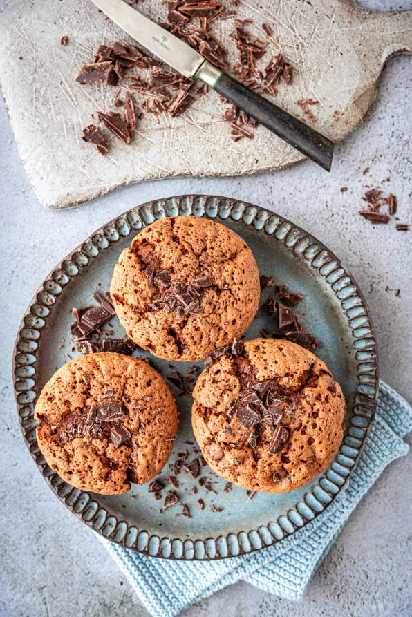 Frisch gebackene Schokomuffins mit Schokostückchen auf einem Keramikteller