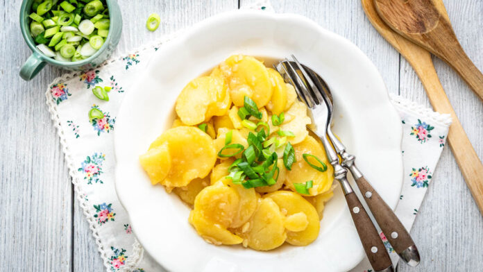wiener-kartoffelsalat-mit-bruehe Wiener Kartoffelsalat mit Brühe auf Teller mit Frühlingszwiebeln