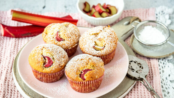 rhabarber-muffins Saftige Rhabarber Muffins mit Puderzucker auf rosa Teller serviert
