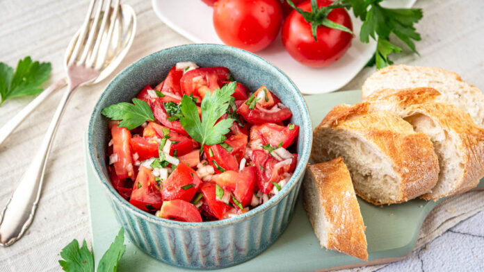 omas-tomatensalat-mit-zwiebeln Tomatensalat mit Zwiebeln und Petersilie in einer Schüssel mit Baguette